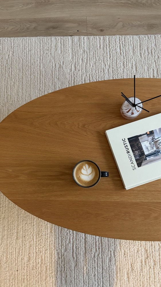 Latte, book and a small vase on an oval oak coffee table